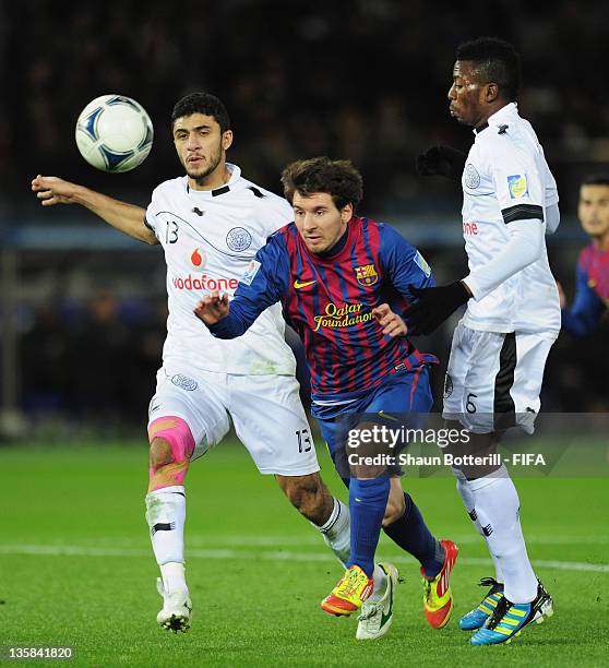 Lionel Messi of Barcelona is challenged by Ibrahim Abdulmajed and Kasola Mohammed of Al-Sadd Sports Club looks on during the FIFA Club World Cup semi...