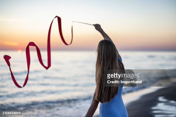 teenage girl dancing with a ribbon on the beach. - ribbon dance stock pictures, royalty-free photos & images