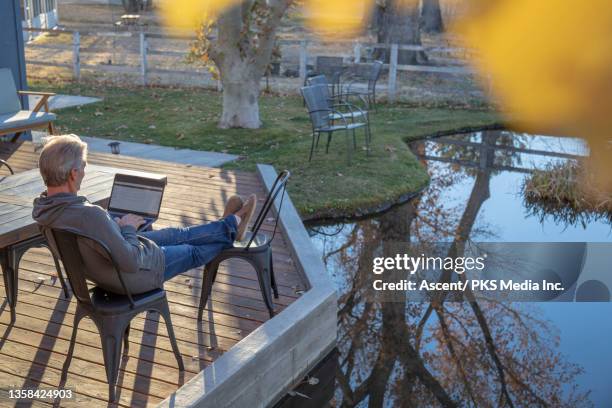 man works on laptop at outdoor table - pond stock pictures, royalty-free photos & images