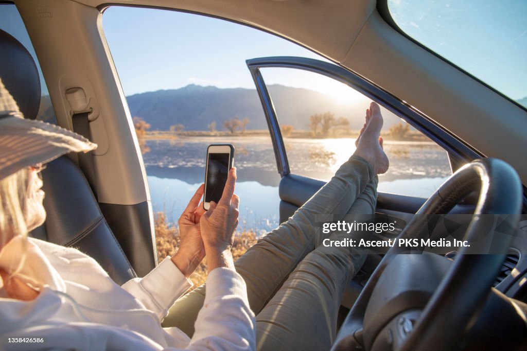 Woman puts her feet up in car, at sunrise