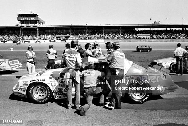 Driver Dale Earnhardt Sr. Sits in his race car surrounded by members of his racing crew prior to the start of the 1983 Firecracker 400 stock car race...