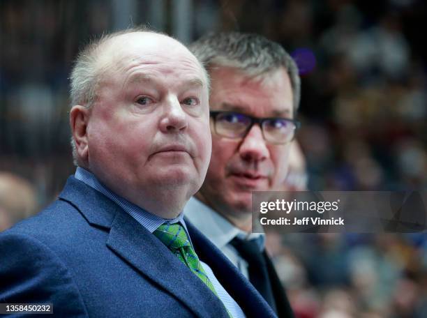 Head coach Bruce Boudreau and assistant coach Scott Walker of the Vancouver Canucks look on from the bench during their NHL game against the Boston...