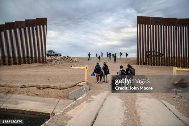 Immigrant families from Haiti walk from Mexico through a gap in the border wall into the United States on December 10, 2021 in Yuma, Arizona. They...