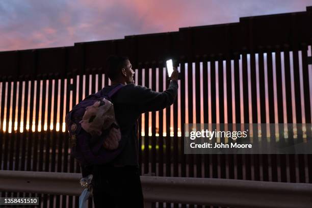 Relieved Venezuelan immigrant speaks with his wife on a video call after he passed through a gap in the U.S.-Mexico border wall after having traveled...
