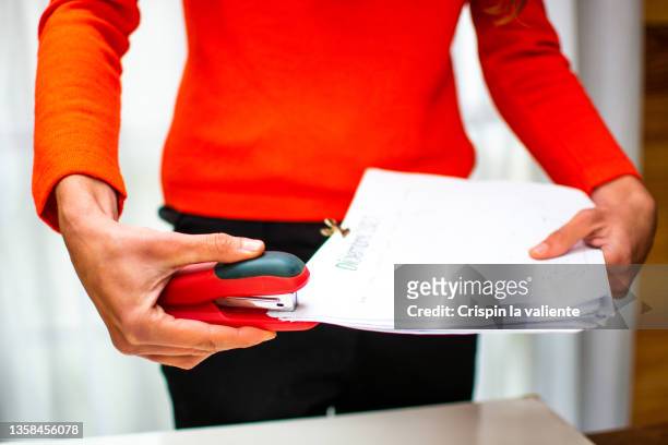woman's hand stapling documents - staples office stockfoto's en -beelden