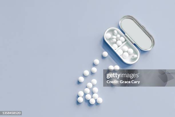 white pills on blue background - melatonin stock pictures, royalty-free photos & images