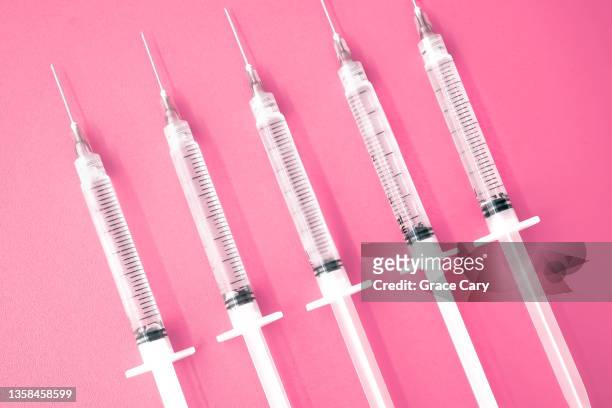 multiple syringes with needles on pink background - nadel stock-fotos und bilder