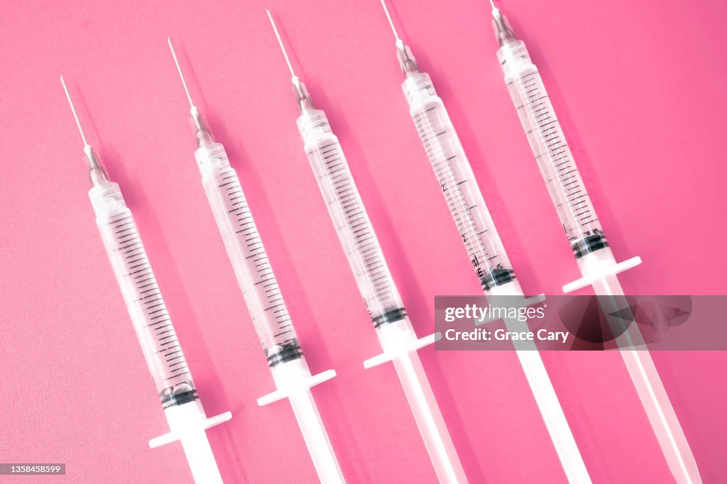 Multiple Syringes With Needles on Pink Background