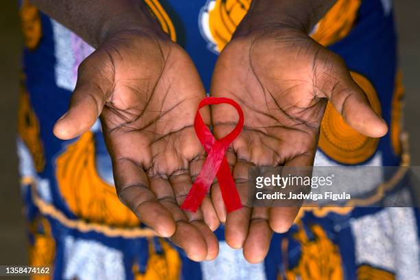 woman holding red ribbon on her palms in burkina faso. - aids foto e immagini stock