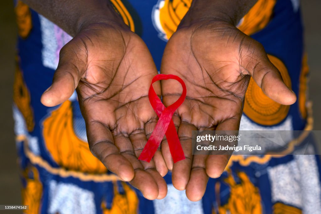 Woman holding red ribbon on her palms in Burkina Faso.