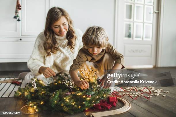 son and mother making christmas wreath at home. - build presents the family stock pictures, royalty-free photos & images