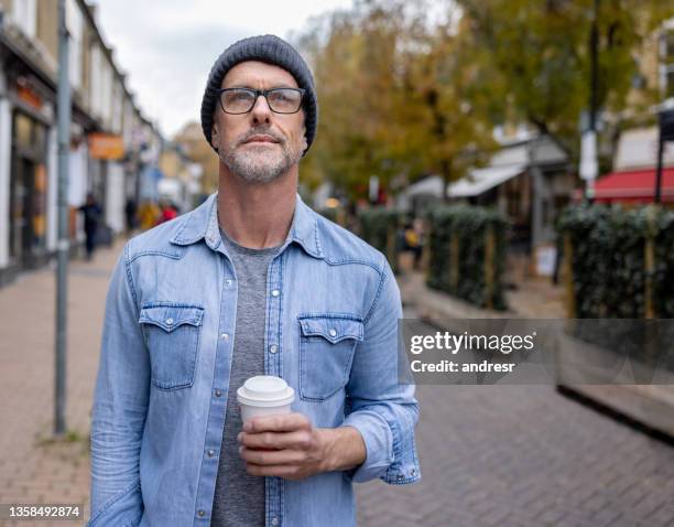 thoughtful man out on the streets drinking a cup of coffee - 40 year old male models stock pictures, royalty-free photos & images