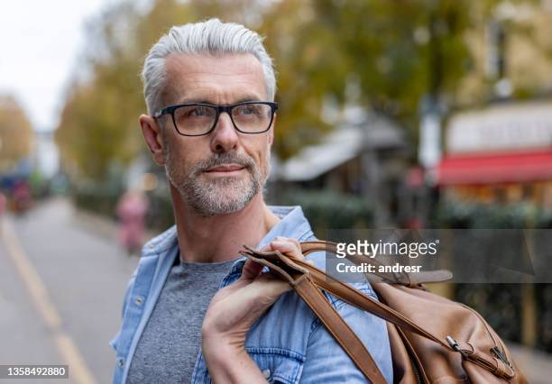 handsome man outdoors commuting to work and carrying a bag - 40 year old male models stock pictures, royalty-free photos & images