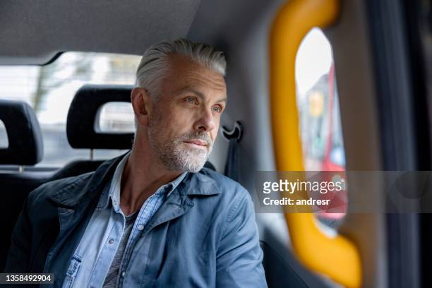 mann, der im taxi fährt und durch das fenster schaut - london taxi stock-fotos und bilder
