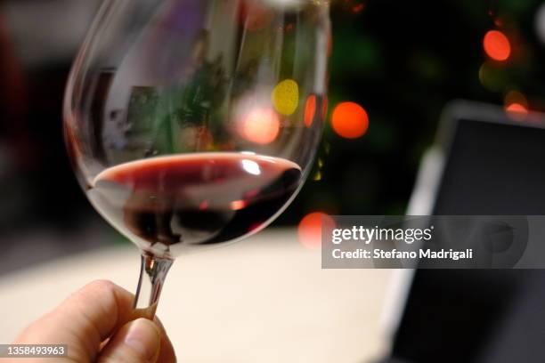 partial section red wine glass with christmas lights in the background - milan cafe stock pictures, royalty-free photos & images