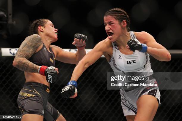 Julianna Pena punches Amanda Nunes of Brazil in their women's bantamweight title fight during the UFC 269 event at T-Mobile Arena on December 11,...