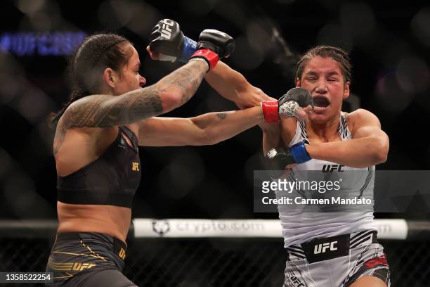 Julianna Pena exchanges punches with Amanda Nunes of Brazil in their women's bantamweight title fight during the UFC 269 event at T-Mobile Arena on...