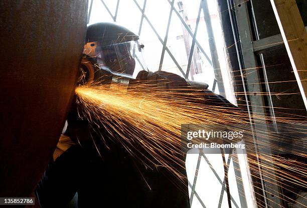 Alstrom Heat Transfer LLC employee Emerson McKoy uses an angle grinder to take the bevel off of a steel cylinder to be used as part of a deaerator at...
