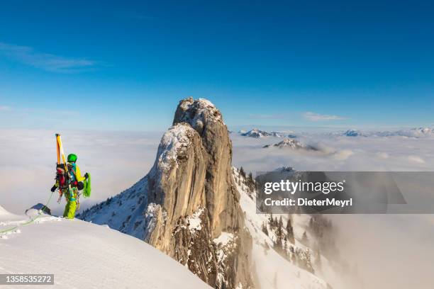 mountaineer man climbs on top snowy mountain with ski at the backpack - crampon stockfoto's en -beelden