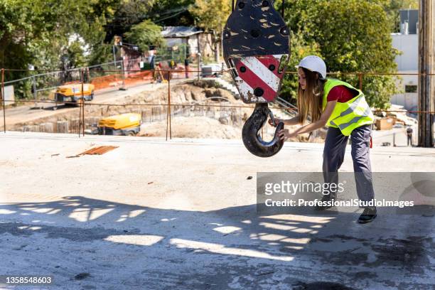 a young female construction worker is working at a construction site. - hook equipment stock pictures, royalty-free photos & images