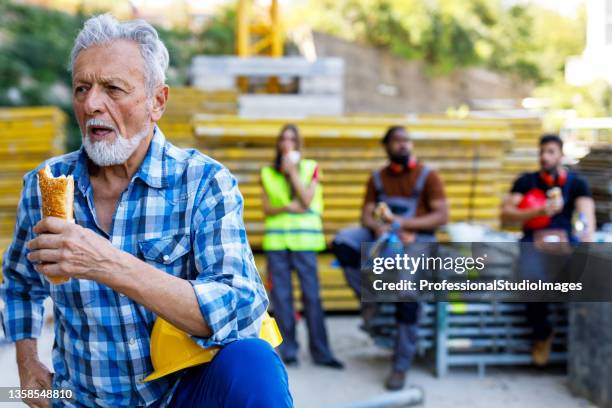 senior construction worker is taking a break and eating. - lunch break stock pictures, royalty-free photos & images