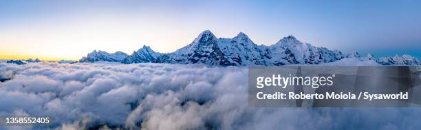 aerial view of snowcapped mountains in winter fog at sunrise - berg mönch stock-fotos und bilder
