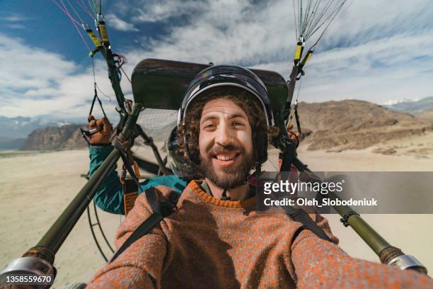selfie of man paramotor flying over katpana desert in northern pakistan - extreme sports stockfoto's en -beelden