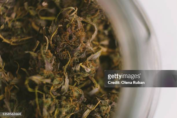 dried cannabis in opened glass bottle. - marihuana hierba de cannabis fotografías e imágenes de stock
