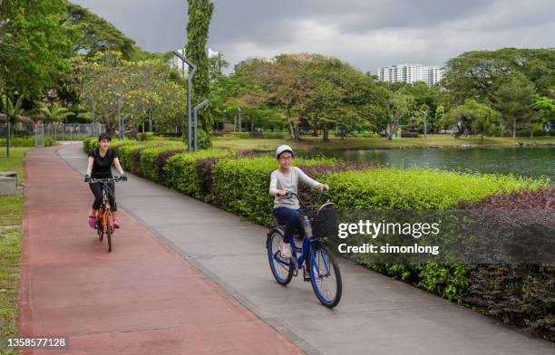 mother and daughter having fun together bikes - kuala lumpur street stock pictures, royalty-free photos & images