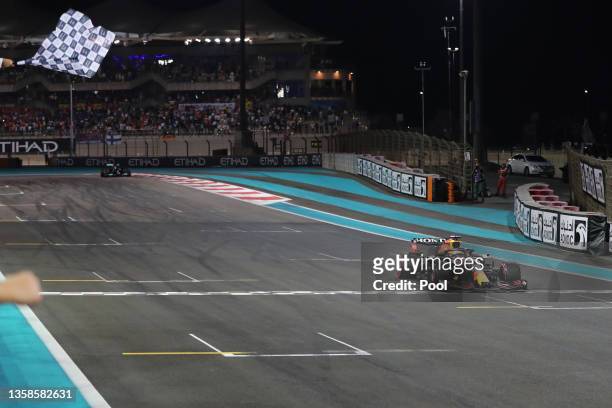 Race winner Max Verstappen of the Netherlands driving the Red Bull Racing RB16B Honda takes the chequered flag during the F1 Grand Prix of Abu Dhabi...