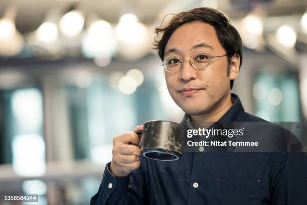 coffee and refreshment breaks improve employee productivity in our business.  thoughtful japanese employees hold coffee cups during taking a break in a modern office at night. - コーヒー　日本人 ストックフォトと画像