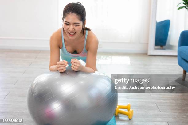 portrait of elegance woman wearing sport's clothing and using exercise ball at her home. - yoga ball fotografías e imágenes de stock
