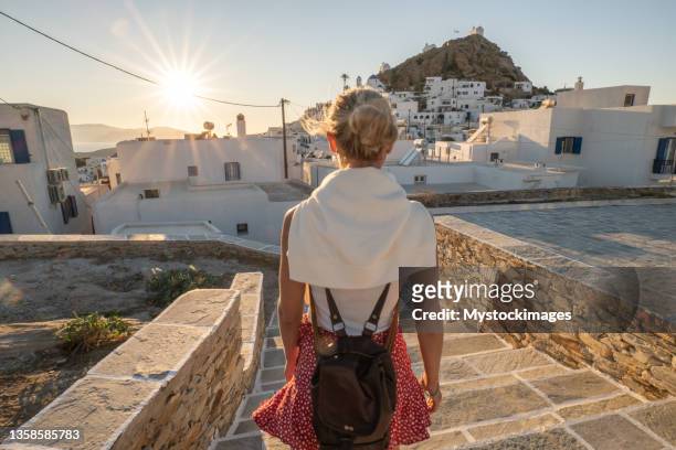 young woman strolling in the narrow greek alleys at sunset - ios grécia imagens e fotografias de stock