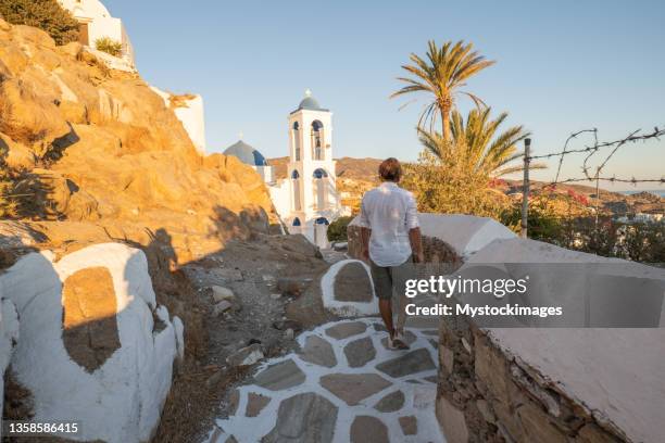 jeune homme se promenant dans les ruelles grecques étroites - ile d'ios grèce photos et images de collection