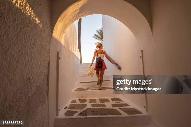 young woman strolling in the narrow greek alleys at sunset - ios greece stock pictures, royalty-free photos & images