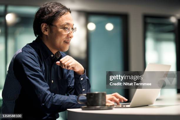 japanese businessman on a conference call with his business partner during working late in a modern office. technology makes communication more effective in business communication. - it happened one night stock-fotos und bilder