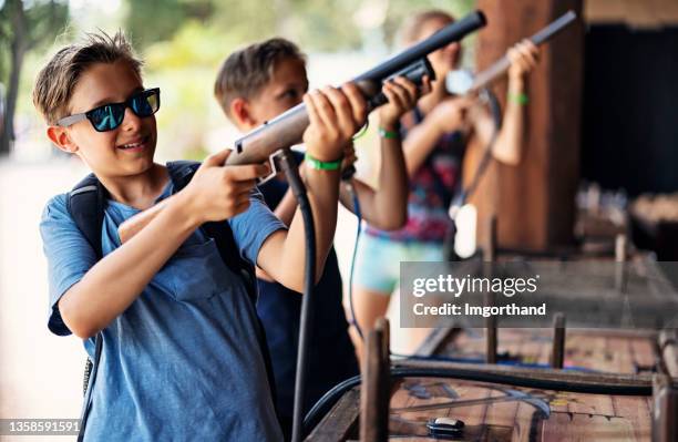 children playing target shooting game at funfair - laser game stock pictures, royalty-free photos & images