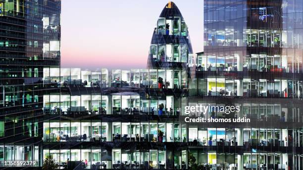 digital composite of illuminated office windows and financial buildings - city of london workers stock pictures, royalty-free photos & images