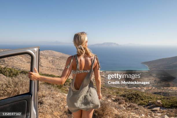 young woman get out of the car to look at panorama, beach view on the greek islands, road trip concept - ios greece stock pictures, royalty-free photos & images