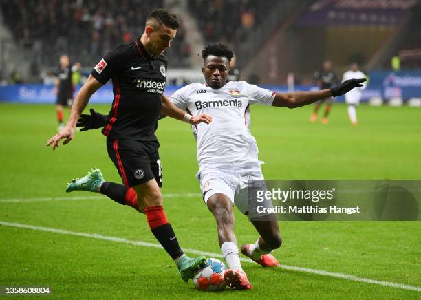 Edmond Tapsoba of Leverkusen challenges Santos Borré of Frankfurt during the Bundesliga match between Eintracht Frankfurt and Bayer 04 Leverkusen at...