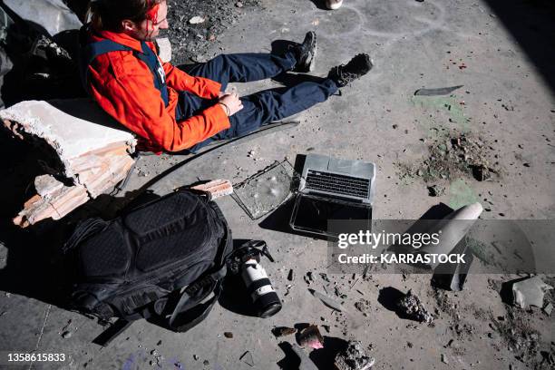 a man, a war journalist with a laptop and digital camera at the scene of the action, in a war zone. - conflict zone stock pictures, royalty-free photos & images