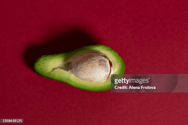 close-up of avocado slice against   red background - avocado oil stock-fotos und bilder