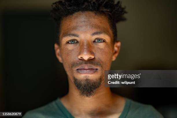close up headshot portrait of young mixed race male face with green eyes facial hair and rasta hair - close up man pose bildbanksfoton och bilder