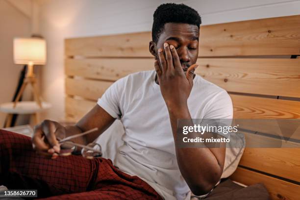 sleepy and tired man rubbing his eyes - black man sleeping in bed stock pictures, royalty-free photos & images