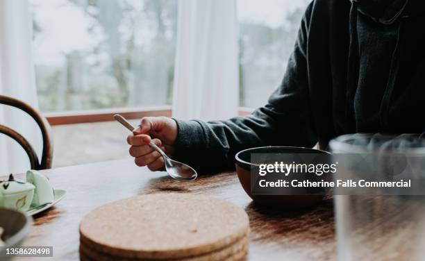 a man sits at a table and eats a bowl of soup - pimentão vermelho assado - fotografias e filmes do acervo
