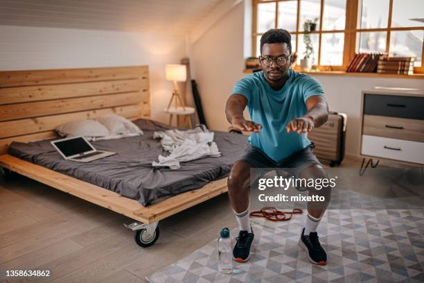 man practicing squats exercise at home - bodyweight training stock pictures, royalty-free photos & images