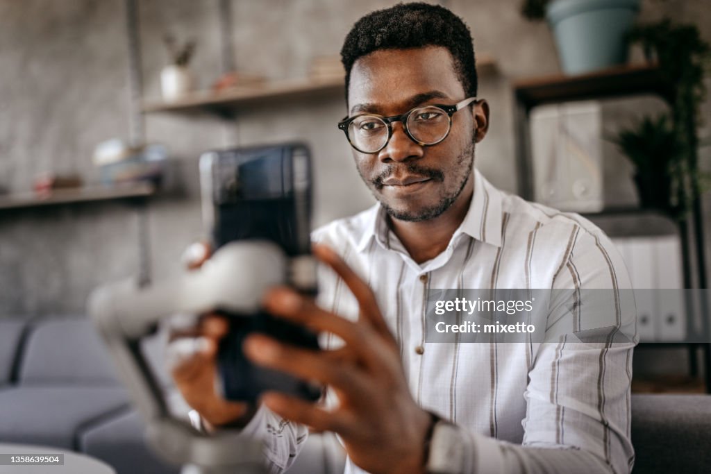 Hombre preparando teléfono inteligente para grabar vlog