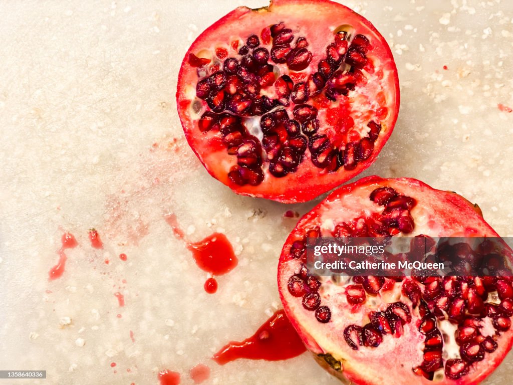 Fresh sliced pomegranate against white cutting board background