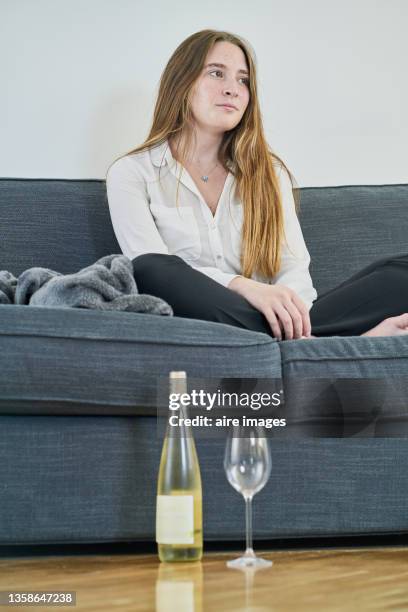 vertical shot of a young woman sitting on the sofa with a drink bottle and shoes on the floor - couch close up stock pictures, royalty-free photos & images