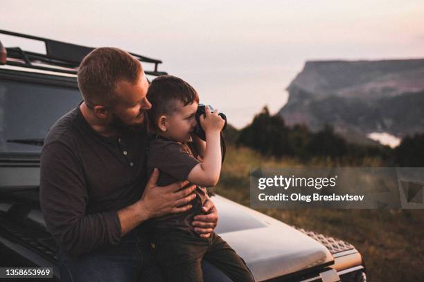 father teaching son to photograph on old film photo camera outdoors at sunset - epic film - fotografias e filmes do acervo
